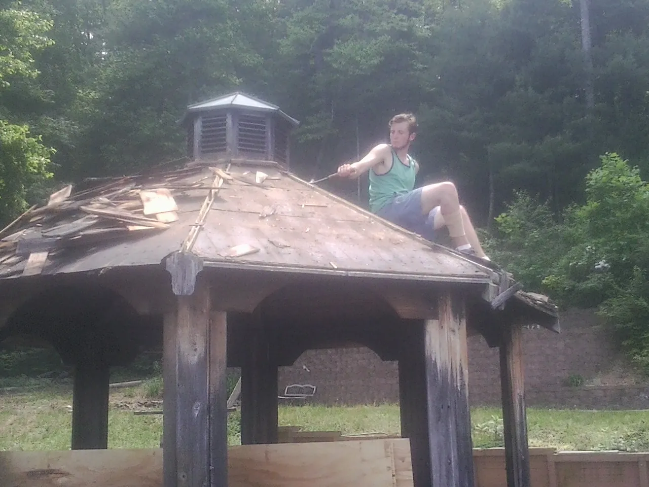 Tearing the old roof off a wooden gazebo before new shakes in Stanley